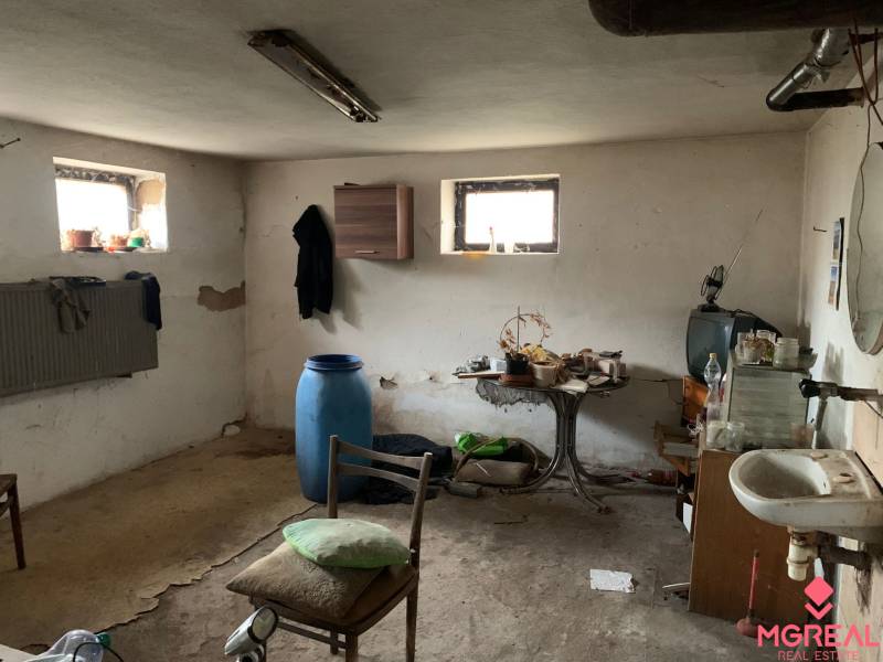 A room in a family house with peeling plaster and various furniture looks neglected.