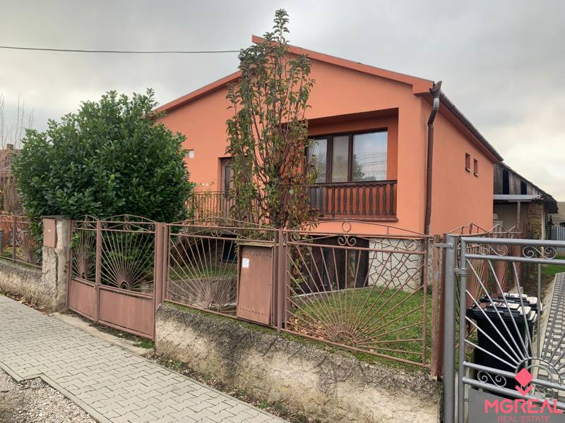 A family house in Lúčnica nad Žitavou with an orange facade, a garden, and a decorative fence.