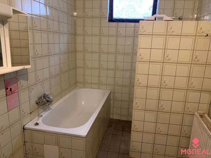 A bathroom in a family house with a white bathtub and tiled walls.