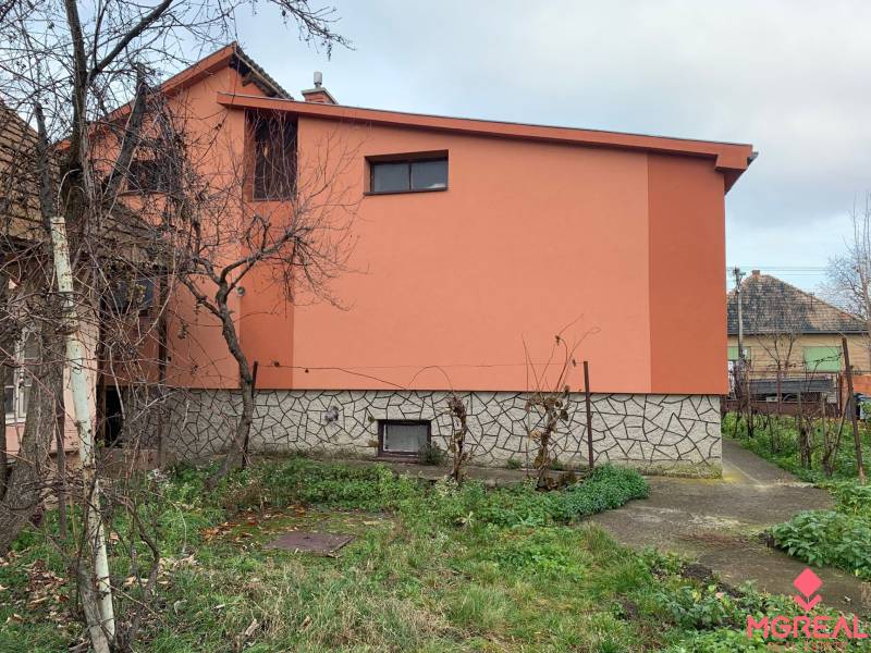 A family house in Lúčnica nad Žitavou with an orange facade and a garden with a walkway.