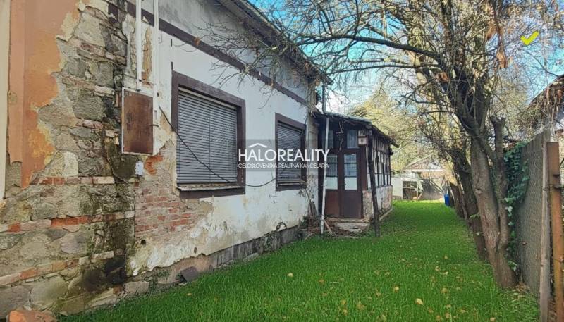 A family house in Rimavská Sobota, with significant signs of wear and a tree in the garden.