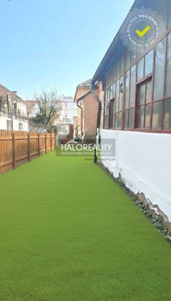 The garden of a family house in Rimavská Sobota with a lawn and a wooden fence.
