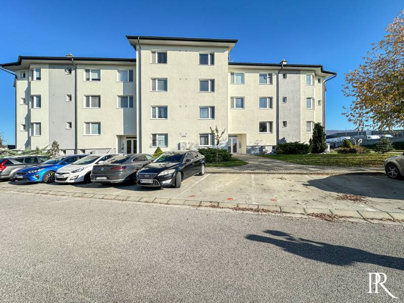 Železničná Street in Trenčianska Turná with parked cars in front of the apartment building.