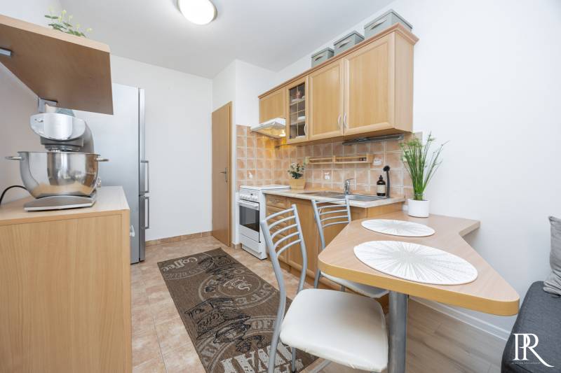 A kitchen in a 2-room apartment with wooden decor and appliances on the counter.