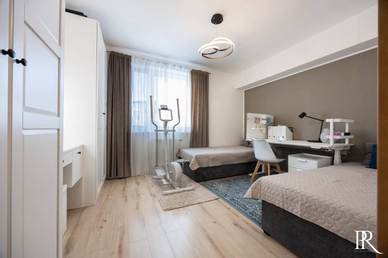 Children's room in a two-room apartment with two beds, a table, and an exercise machine.