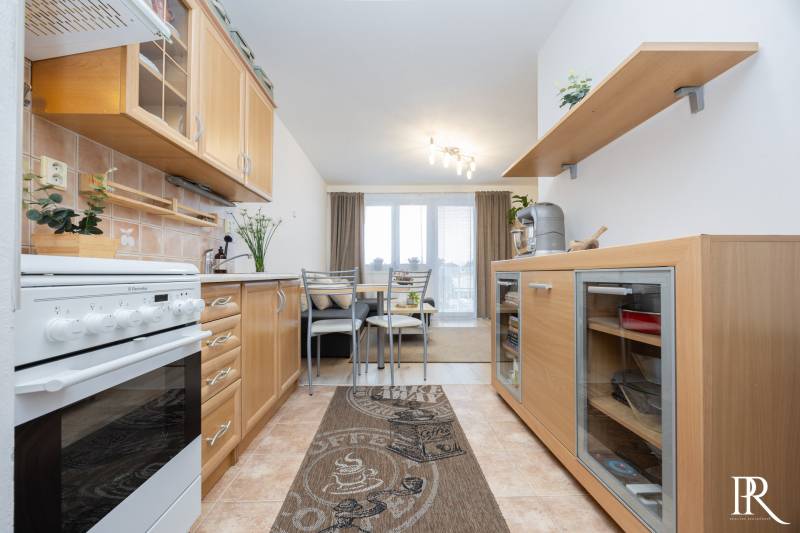 A kitchen in a 2-room apartment with a wooden decor and a dining area.
