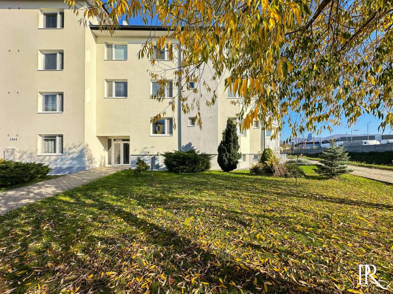 An apartment building in Trenčianska Turná on Železničná Street surrounded by greenery and trees.