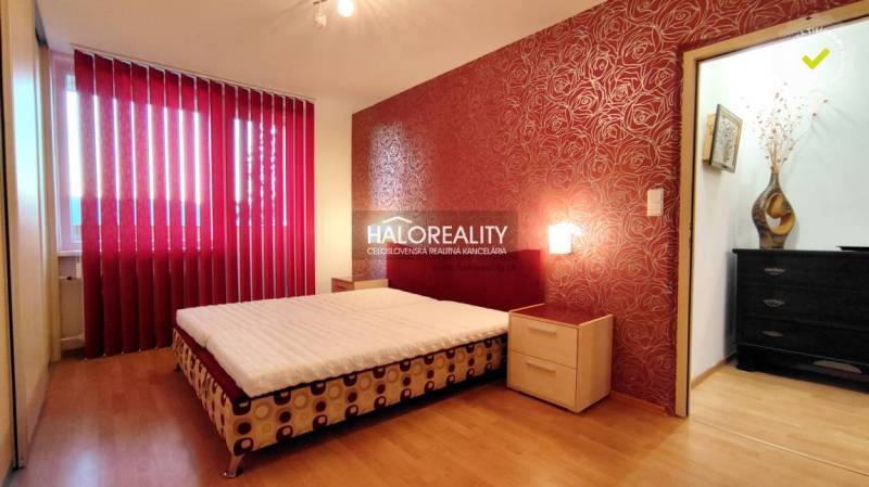 A bedroom with patterned red wallpaper, a bed, and a wardrobe in a 2-room apartment.