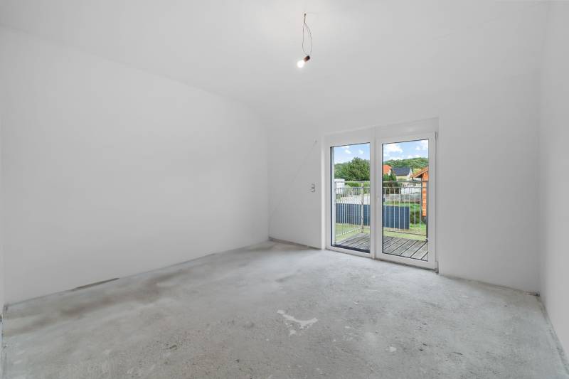 An empty room with a concrete floor and large French doors in a family house.