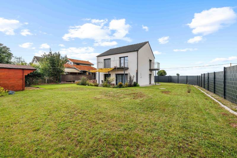 A family house on Breitensee Street in Marchegg with a well-maintained lawn and a wooden shelter.