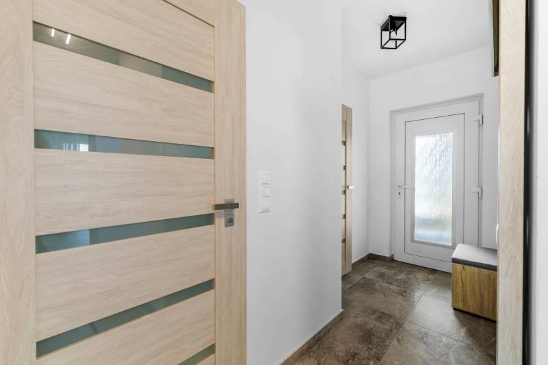 Entrance hallway in a family house with laminate and glass doors.