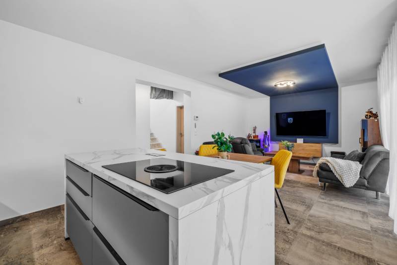 Living room in a family house with a kitchen island, seating, and television.