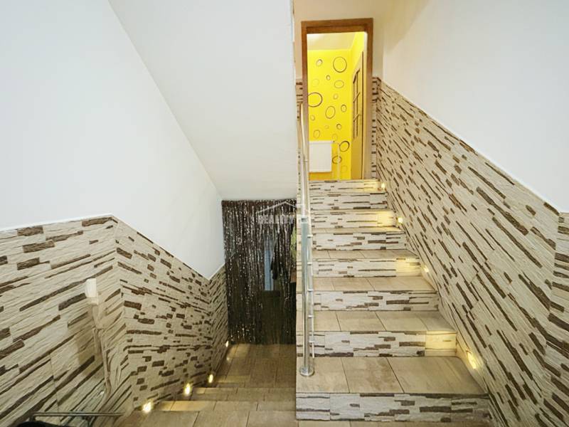 A staircase in a family house with cladding and lighting, leading to the upper floor.