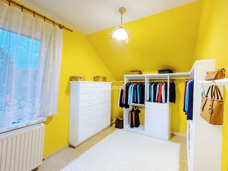 A wardrobe in a family house with colorful walls, white furniture, and a curtain.