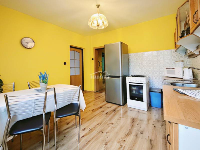 A kitchen in a family house with a wooden decor floor, yellow walls, and appliances.