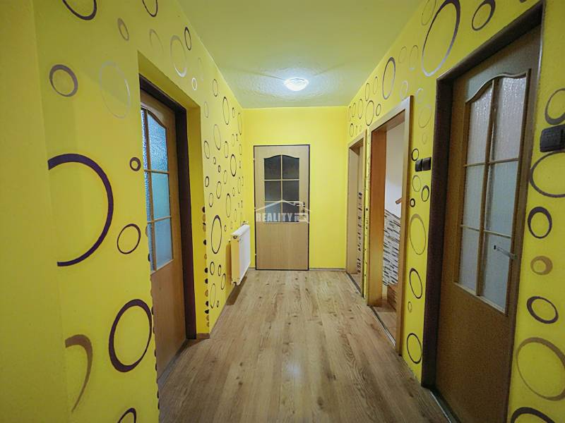 A hallway in a family house with colorful walls and a wooden decor floor.