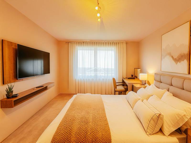 Bright bedroom in a family house with a TV, a desk, and a comfortable bed.