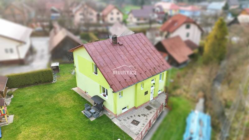 A family house in Kysucké Nové Mesto with a green facade and a metal roof.