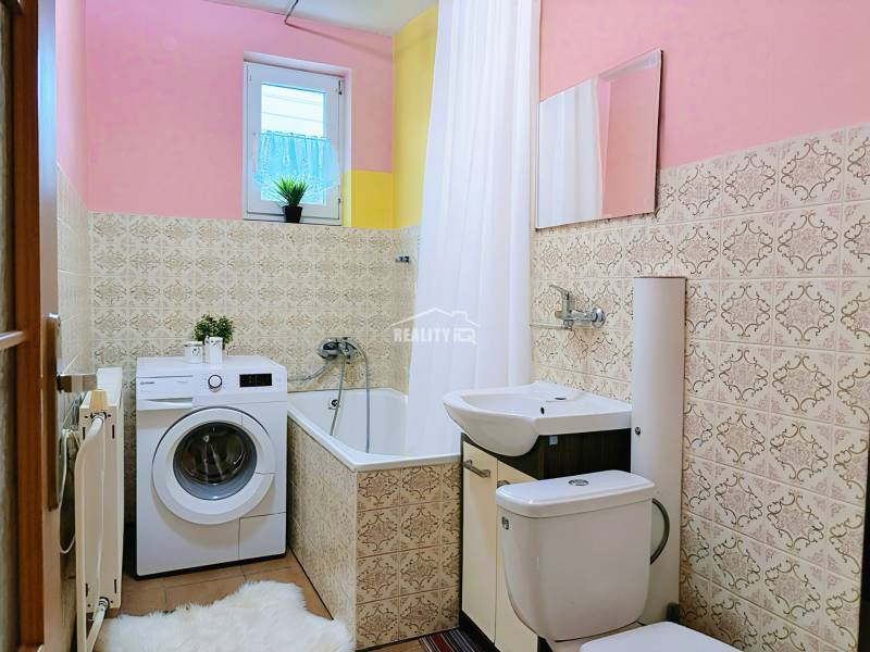 Bathroom in a family house with a sink, washing machine, and bathtub, decorative tiles on the walls.