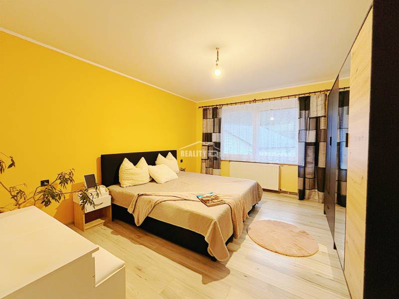 A bedroom in a family house with a wood-patterned floor and yellow walls.