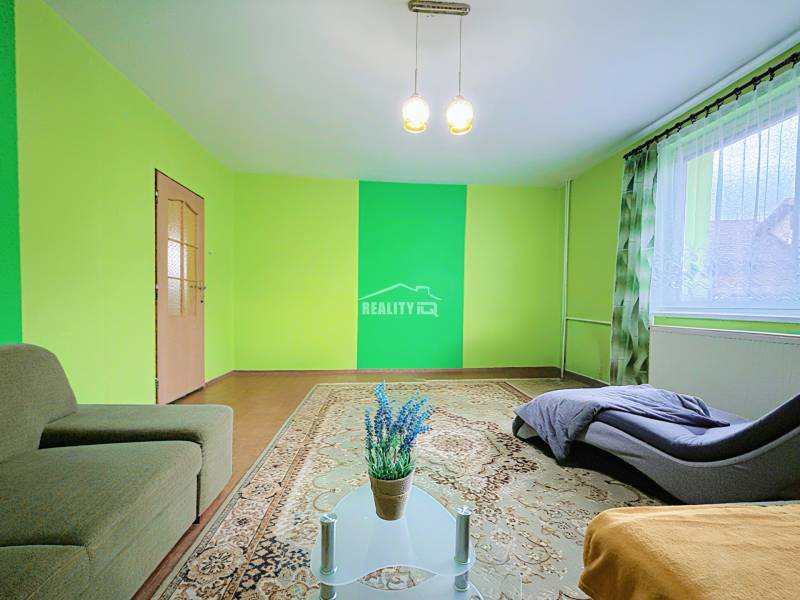 Living room in a family house with colorful walls, a sofa, and a large carpet.
