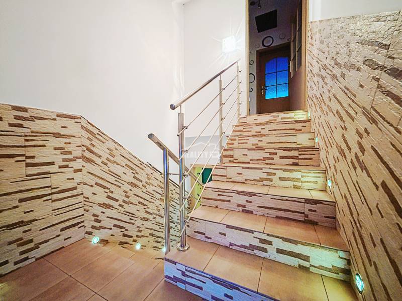 A staircase with stone decor and stainless steel railing in a family house.