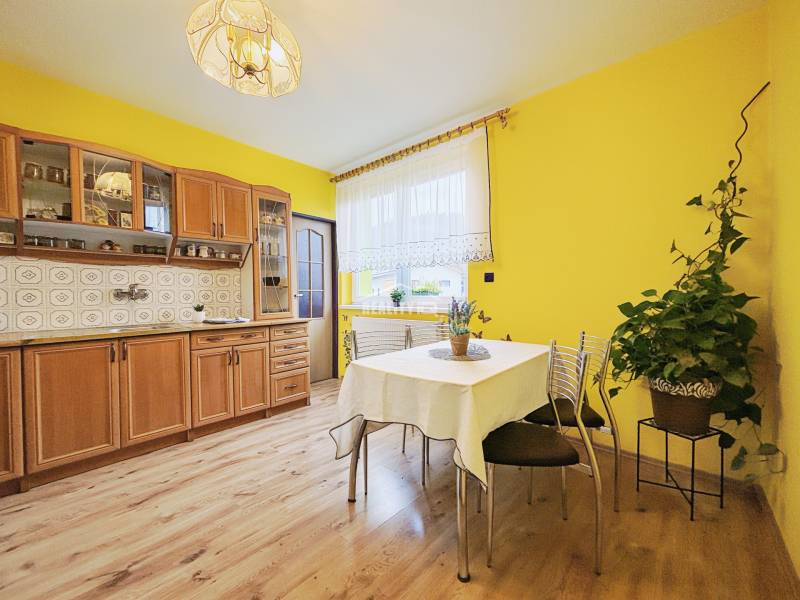 A kitchen in a family house with yellow walls and a wooden decor floor.