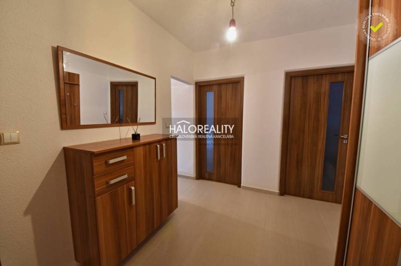 A hallway in a 2-room apartment with a wooden decor on the doors and cabinet, mirror on the wall.