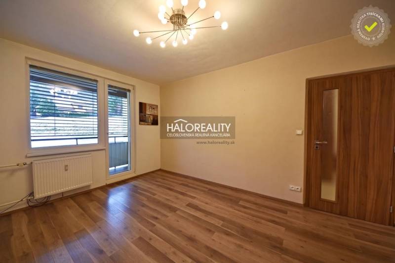 A spacious room with a wooden decor floor and a large window in a 2-room apartment.