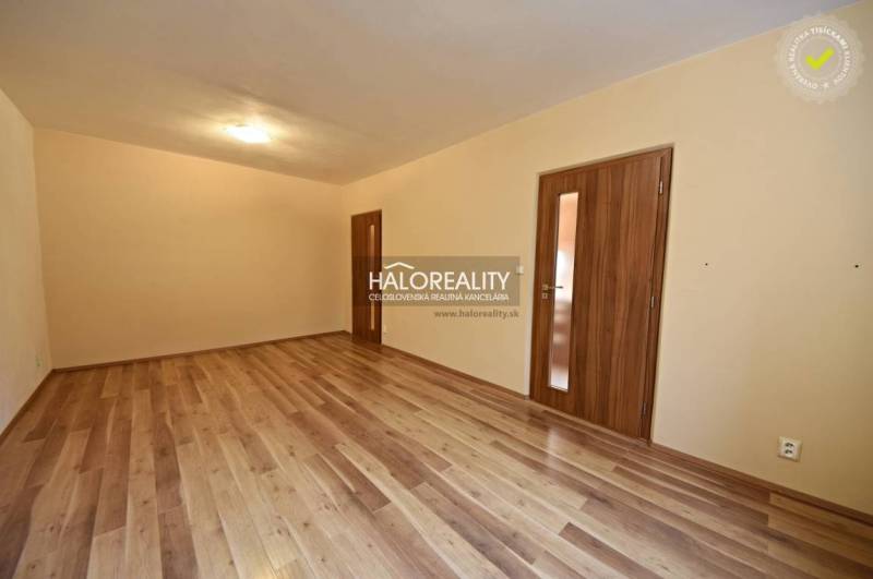 A spacious room with a wooden decor floor and two doors in a 2-room apartment.