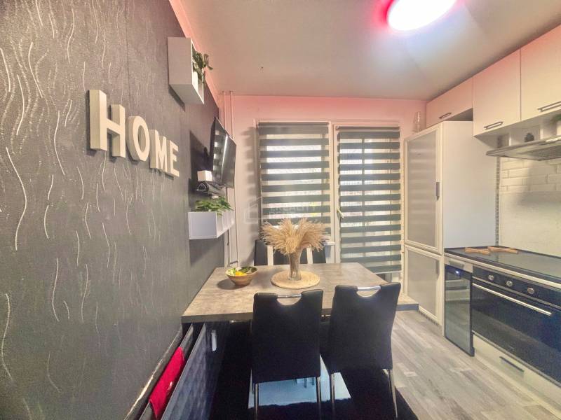 A kitchen in a 3-room apartment with a dining table and a floor with a wooden decor.