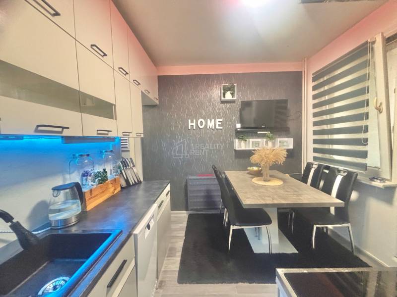 A kitchen in a 3-room apartment with a wooden decor floor, a dining table with chairs.