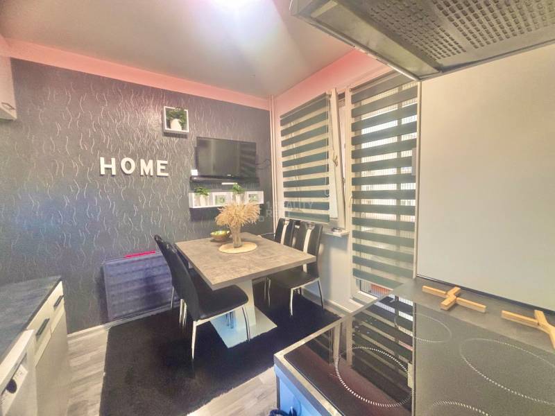 Kitchen in a 3-room apartment with a dining table, television, and the word 