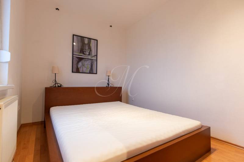 Bedroom with a bed and a decorative picture, wooden decor flooring, studio apartment.