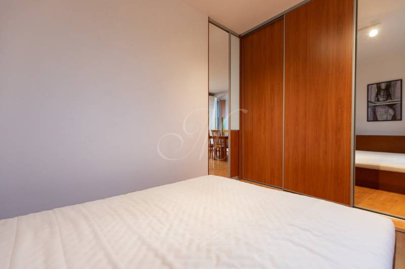 In the one-room apartment, there is a built-in wardrobe with a wood decor next to the bed.