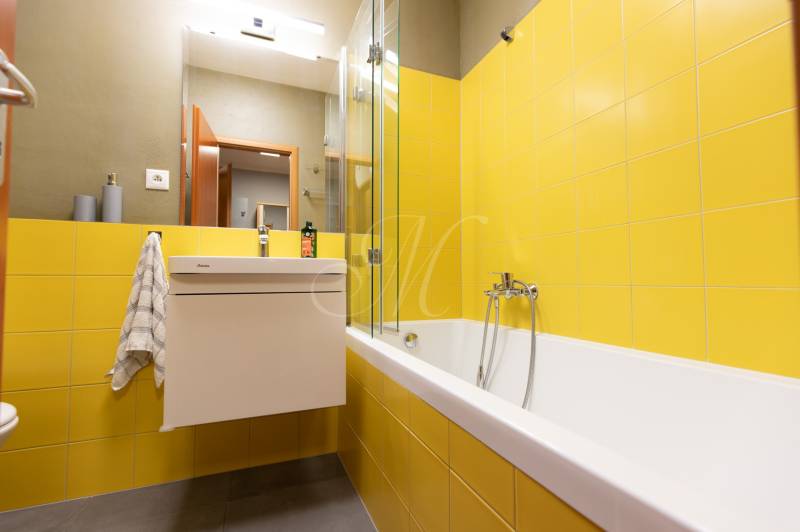 Bathroom with a bathtub and yellow tiles in a studio apartment.