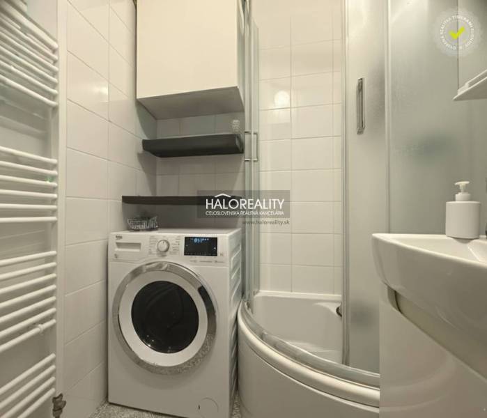 A bathroom in a 3-room apartment with a washing machine, shower, and white tiles.