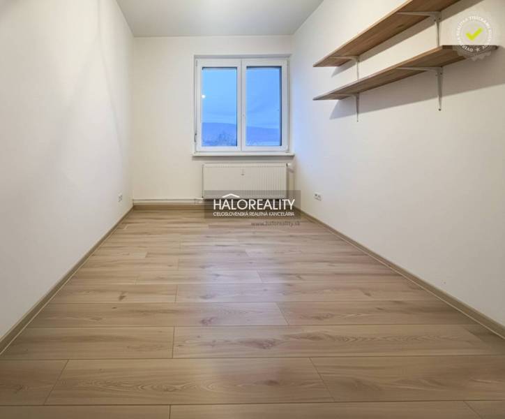 A room in a 3-room apartment with a wooden decor floor and shelves on the wall.