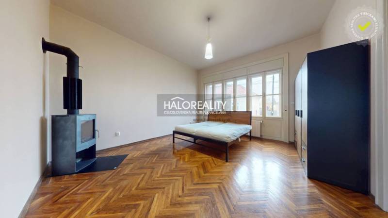 Interior of a 3-room apartment with a bed, fireplace, and wooden decor flooring.
