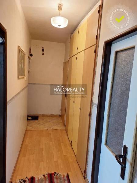 A narrow hallway with built-in wardrobes and a wood-patterned floor in a three-room apartment.