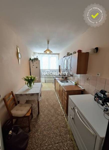 A kitchen in a 3-room apartment with a carpet, kitchen unit, and dining table.
