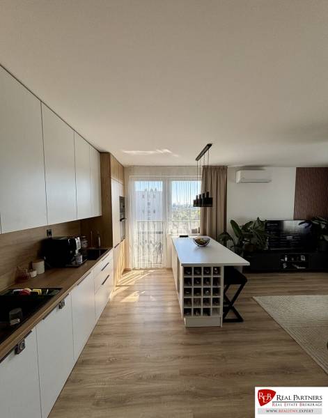 A kitchen in a 3-room apartment with a wooden decor floor and an island.