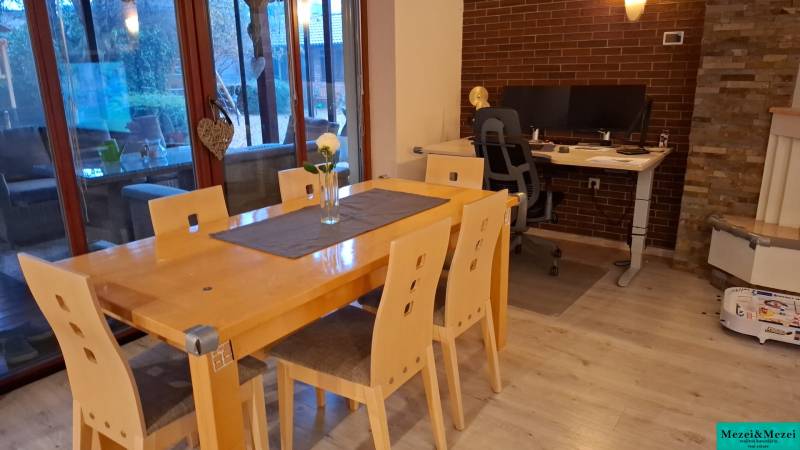 Dining room in a family house with a wood-patterned floor, wooden table, office-work corner.