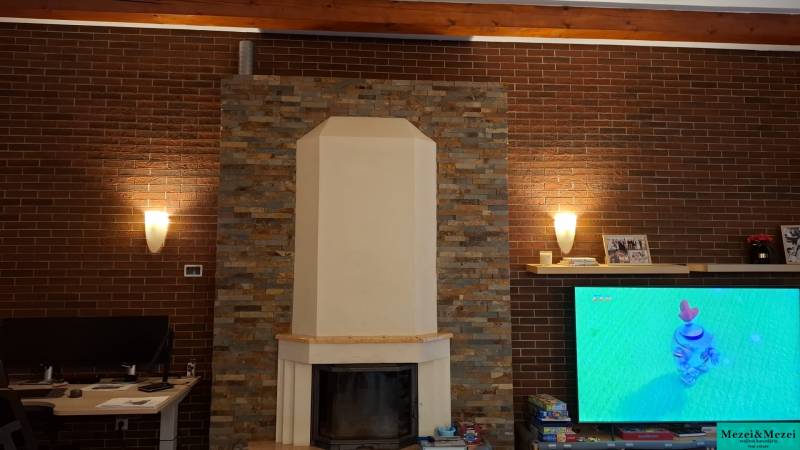 Interior of a family house with a fireplace and a television screen on a brick wall.