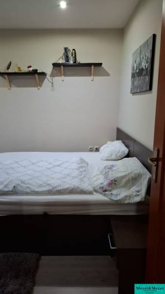 Bedroom in a family house with a bed, shelves, and a picture, floor with wooden decor.