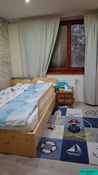 Children's room in a family house with a bed, a carpet with a pirate motif, and curtains.