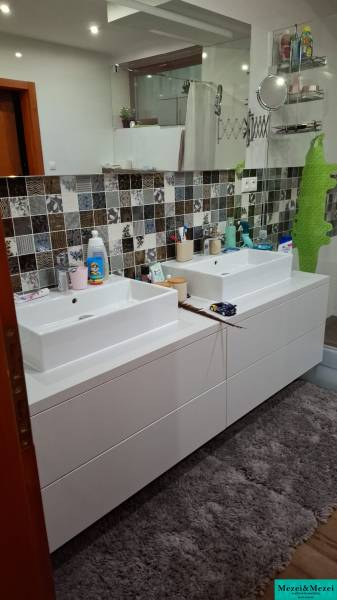 A bathroom in a family house with a double sink, colorful tiles, and a carpet.