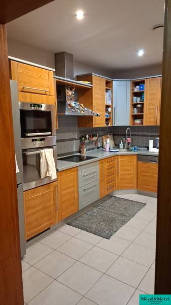 A kitchen in a family house with wooden cabinets and appliances, tiled floor.