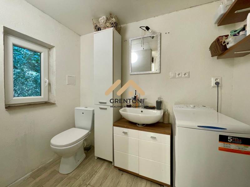 Bathroom in a cabin with a sink, washing machine, and toilet, floor with wooden decor.