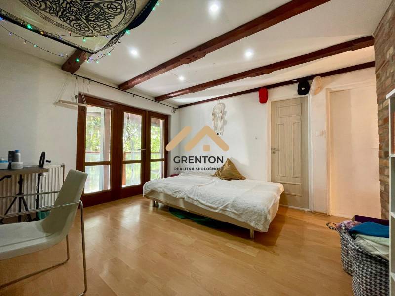 Interior of a cabin with a bed, chair, and floor with wooden decor.